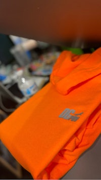 an orange hoodie is sitting on a desk